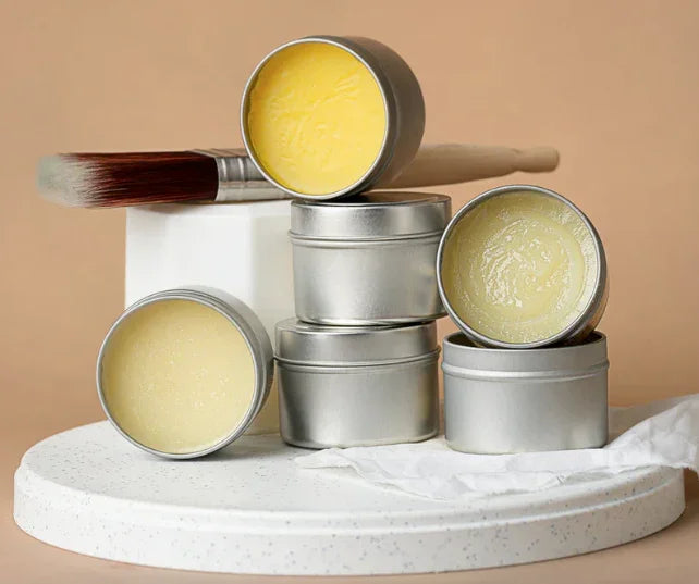 Furniture wax tins and paintbrush displayed on a white tray for furniture refinishing