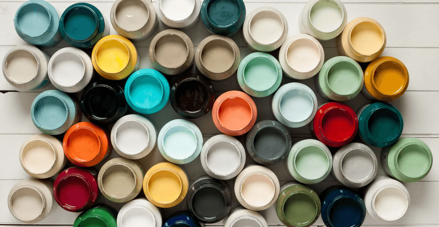 Assorted small containers of different colors arranged in a pattern on a light wooden surface.